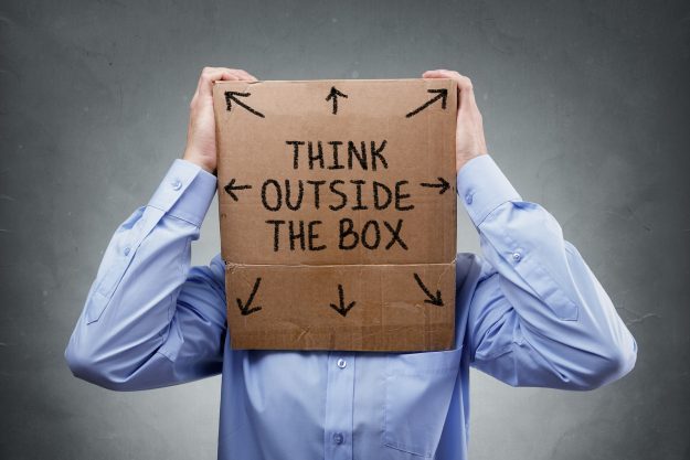Businessman with cardboard box on his head saying think outside Businessman with cardboard box on his head saying think outside the box concept for brainstorming, creativity, innovation, strategy or individuality