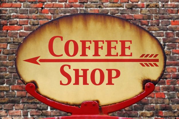 A rusty old retro arrow sign with the text Coffee shop A rusty old retro arrow sign with the text Coffee shop