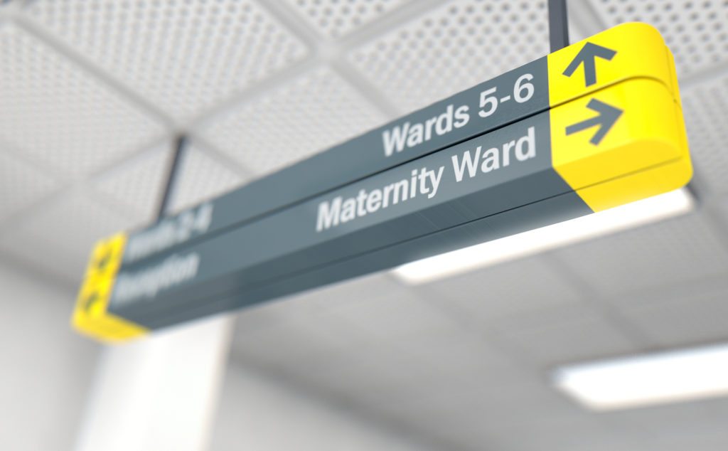 A ceiling mounted hospital directional sign highlighting the way towards the maternity ward - 3D render