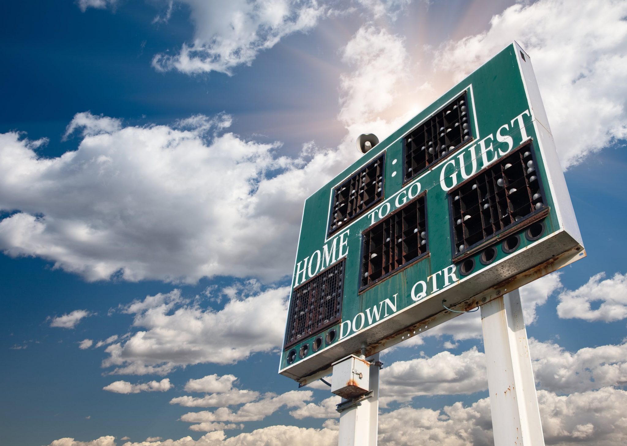 HIgh School Score Board on a Dramatic Blue Sky with Clouds and Sun Rays.