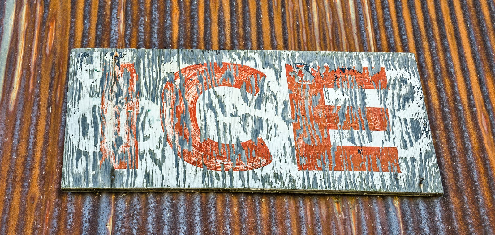 Rust on the corrugated metal and weathering of the wood sign for ice