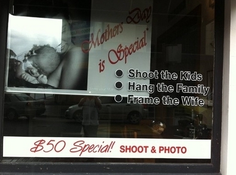 Window ad for photgrapher that says "Shoot the kids, Hang the family, Frame the wife"