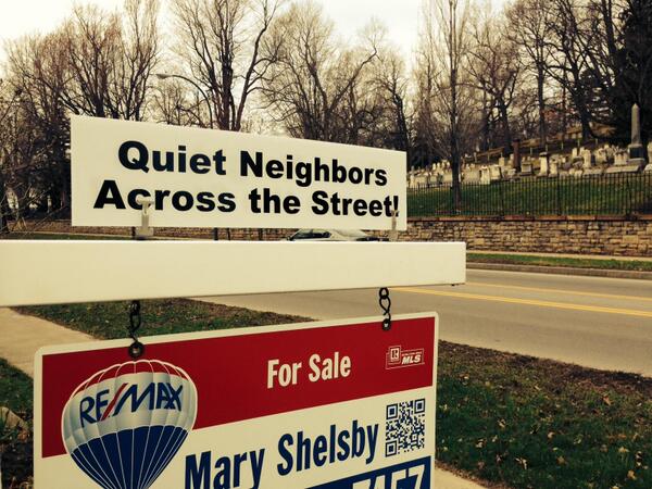 For sale sign next to cemetery that says "quiet neighbors across the street"