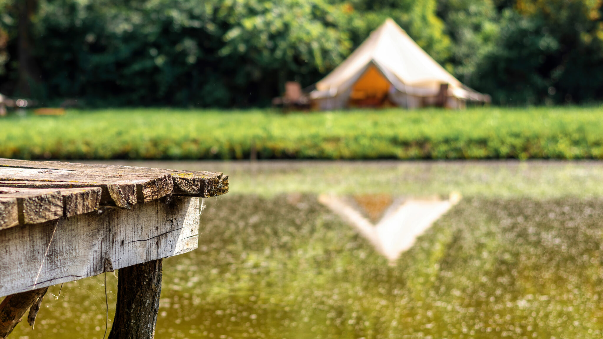 Wooden pier for rest near a lake with tent on the background at glamping Campgrounds need clear signage in order for visitors to stay safe and have fun