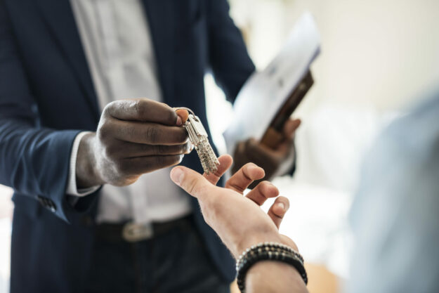 Real estate agent handing the house key to a client Real estate agent handing the house key to a client