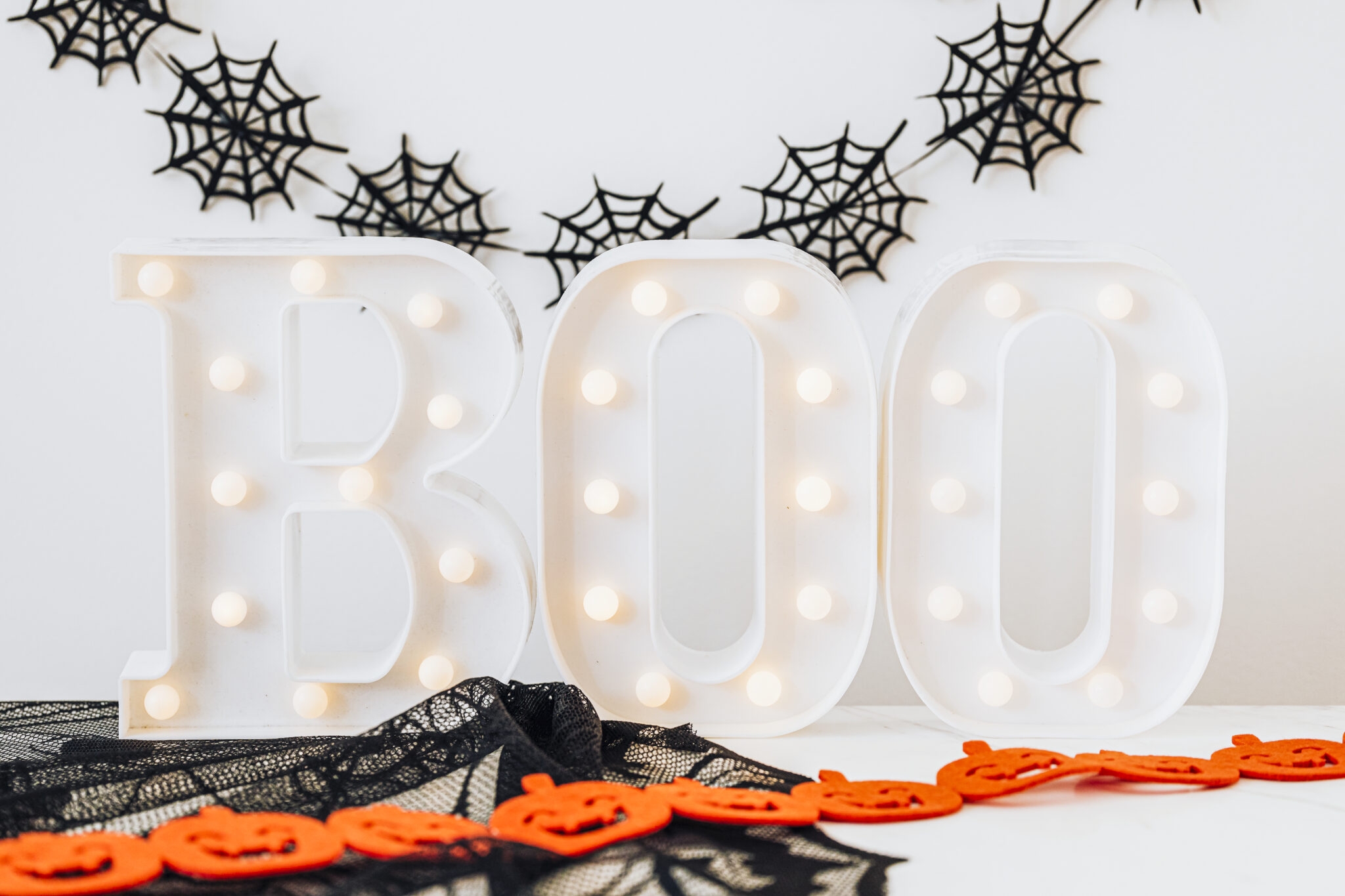 Lighted boo sign on a white table with Halloween decoration