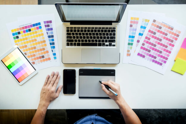 Top view of a young graphic designer working on a desktop comput Design a great look to update your digital sign with!