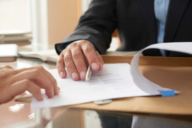 Business people signing a contract Getting permits for your signage can be a major hassle unless you have the help of a signage company to guide you