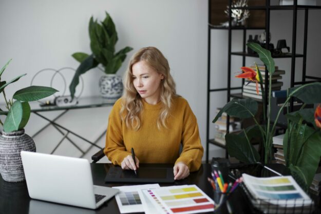 female-logo-designer-working-her-tablet-connected-laptop Designing your signs right can help to boost revenue for your small business.