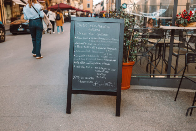 Black Restaurant menu chalkboard on the street. A menu chalkboard with a list of dishes in front of a restaurant in a pedestrian street in Pisa, Italy.