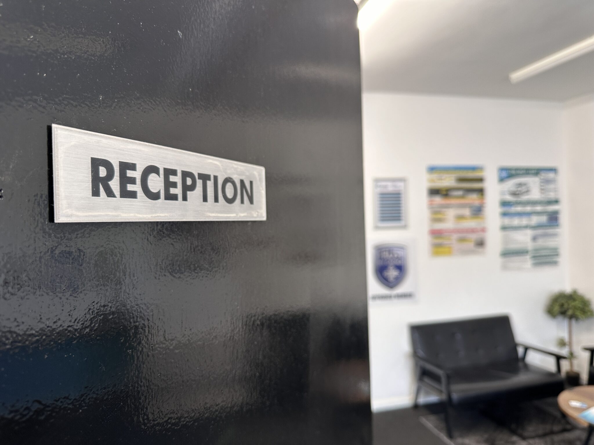 Rewception sign on a black door, waiting area with couch on background